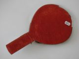 a red ping pong paddle on a white surface