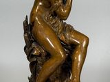 une photo d'une statue en bronze représentant une femme assise sur une souche d'arbre