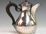 a silver tea pot with a handle on a table