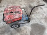 une tondeuse à gazon rouge et bleue posée sur un sol en béton