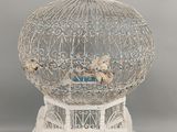 une cage blanche contenant un oiseau