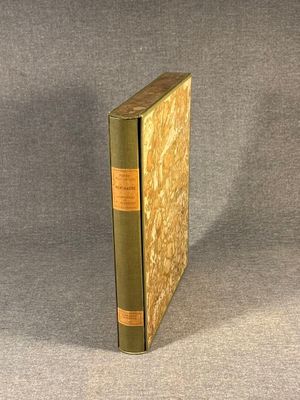 an old book sitting on top of a gray cloth covered table
