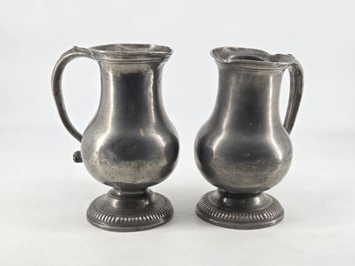 two silver vases sitting next to each other on a table