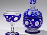 a blue vase and a wine glass sitting next to each other