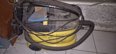 un aspirateur jaune et noir posé sur un sol carrelé