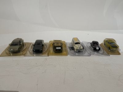 several toy cars are lined up in plastic bags on a white surface