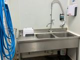une photo d'une salle de bains avec un lavabo et un tuyau accroché au mur