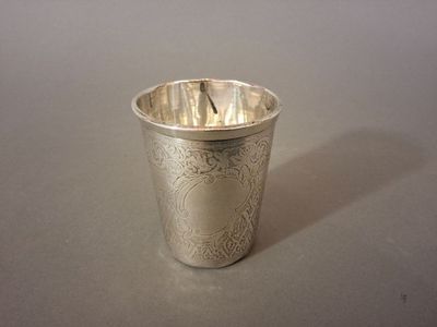 une tasse en argent posée sur une table, avec une cuillère à l'intérieur