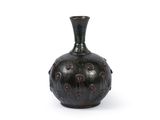 un vase noir posé sur une surface blanche, avec un fond blanc