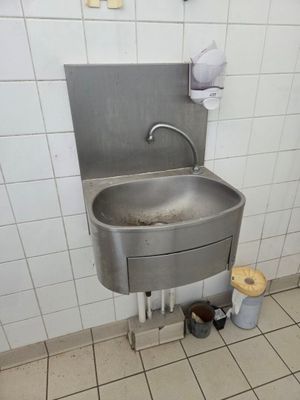 a sink in a public restroom with a trash can