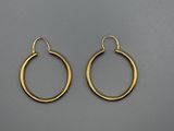 une paire de boucles d'oreilles créoles en or sur fond gris