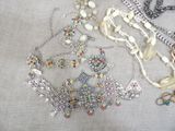 many different necklaces and bracelets laid out on a table