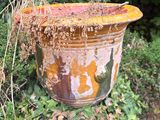 a rusted pot sitting on the ground in the grass
