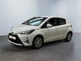 une Toyota Yaris blanche garée dans une pièce au sol noir