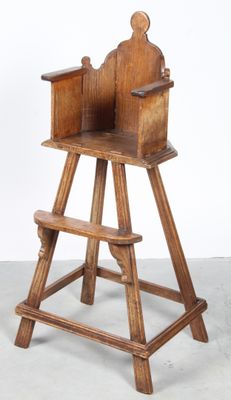 an old wooden high chair sitting on top of a cement floor