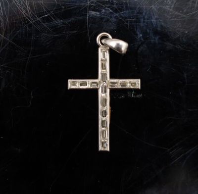 un gros plan d'une croix en argent sur fond noir