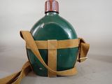 a green bottle with a strap around it on a table