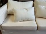 a white couch with two pillows on it in a living room