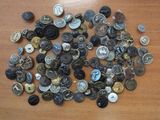 a pile of buttons on a table with a clock in the background