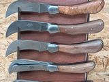 five knives in a wooden holder with a sign on it