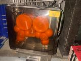 carrots in a juicer sitting on top of a counter next to a pile of boxes