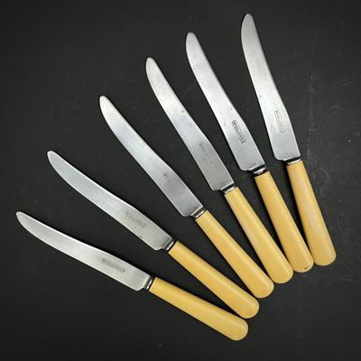 six couteaux sont alignés les uns à côté des autres sur une surface noire