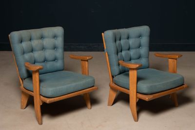 une paire de fauteuils rembourrés bleus avec des accoudoirs et des pieds en bois