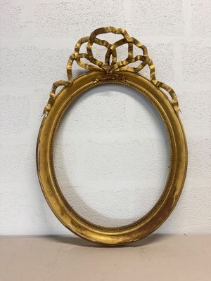 a gold picture frame sitting on top of a table next to a wall