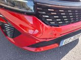 the front end of a red car with a number plate on it