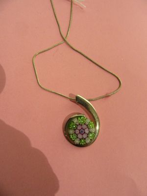 a close up of a necklace with a green flower on it