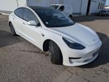 the white tesla model 3 is parked in front of a building