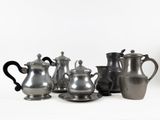 a group of silver teapots and cups on a white surface