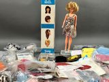 une poupée Barbie assise à côté d'une boîte de vêtements