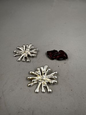 deux flocons de neige en argent posés sur une table, à côté d'un fruit