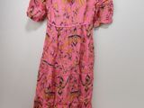 pink floral dress on a hanger against a white wall