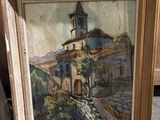 painting of a church in a frame on the floor next to a pile of boxes
