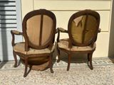 pair of antique wooden chairs with upholstered arms and back cushions