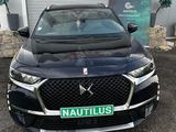 the front end of a black car parked in front of a garage