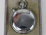 a small silver pocket watch in a box on a table