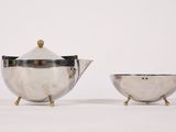 two silver teapots and a bowl on a white surface