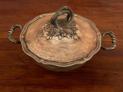 a silver bowl with a handle on a wooden table
