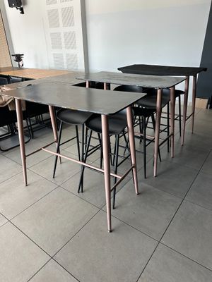 tables and stools in a room with a white wall and tile floor