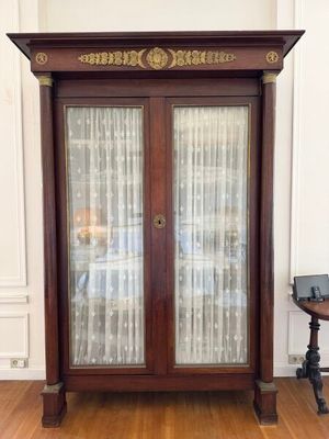 a wooden cabinet with a glass door in the corner of a room