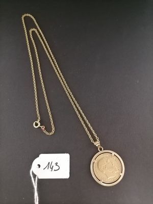 a gold necklace with a coin and a tag on it