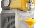 a juicer with a glass of orange juice next to it