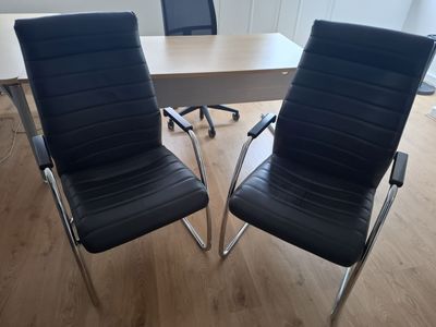 pair of black leather office chairs in front of a wooden table