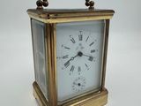 une horloge de voyage ancienne en laiton, avec des chiffres romains sur le cadran