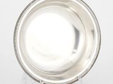 assiette en argent plaqué avec bord perlé, posée sur un support, sur fond blanc