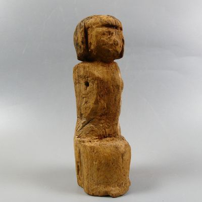 a wooden sculpture of a woman sitting on a stool