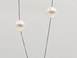 un gros plan d'un collier de perles blanches monté sur une chaîne en argent